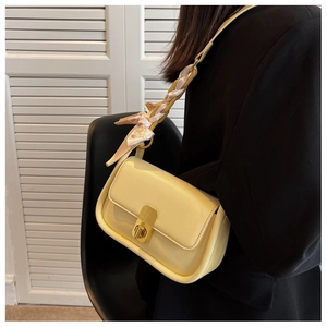 Détail d'un sac jaune avec fermoir doré et foulard élégant en soie sur la bandoulière