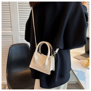 Mini sac bandoulière crème porté avec un sweat noir pour un contraste élégant