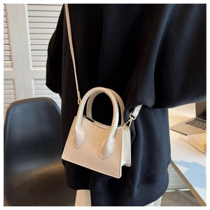 Détail d'un mini sac à main beige avec des finitions dorées et une bandoulière amovible