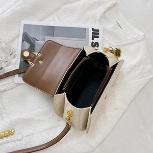 Detail view of the cream and brown leather bag showing inner compartments and gold hardware