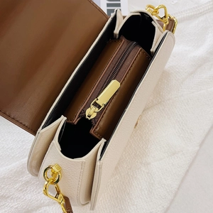 Detail view showing interior zipper compartment and beige pebble grain texture of the bag