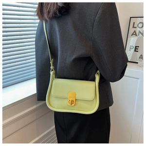 Détail du sac à bandoulière vert avocat avec bords arrondis et fermoir doré sur un modèle
