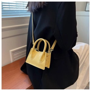 Détail d'un mini sac bandoulière jaune sur un mannequin avec une forme trapèze élégante
