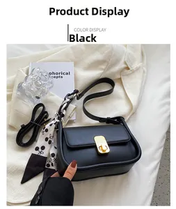 Détail du sac bandoulière en cuir noir avec fermoir doré et foulard en soie à motifs