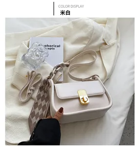 Détail du sac à bandoulière crème avec foulard en soie et fermoir doré sur veston