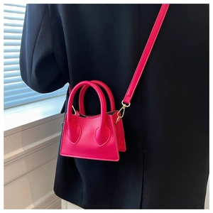 Détail d'un mini sac à main rose fuchsia en simili cuir avec des finitions dorées