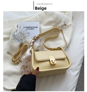 Détail sac bandoulière jaune en similicuir avec foulard floral et fermoir doré