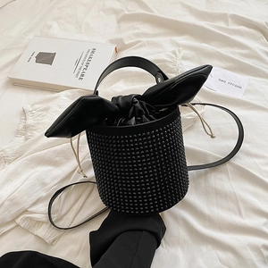 Fashionable black rhinestone bucket bag with rabbit ear bow and studs on white background