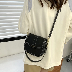 Black leather saddle bag with white contrast stitching and adjustable crossbody strap