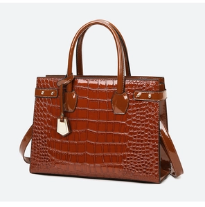 Detailed view of crocodile embossed leather handbag with glossy finish and gold hardware