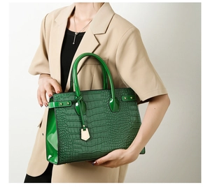 Detailed view of dark green crocodile texture handbag with gold metal pendant accent