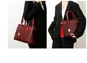 Detail view of deep red crocodile pattern leather handbag with adjustable shoulder strap