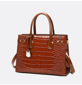 Close-up of brown crocodile embossed tote bag with gold hardware and smooth glossy finish