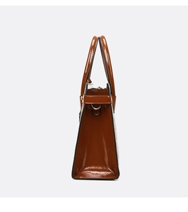 Detailed side view of brown patent leather tote bag with embossed crocodile texture
