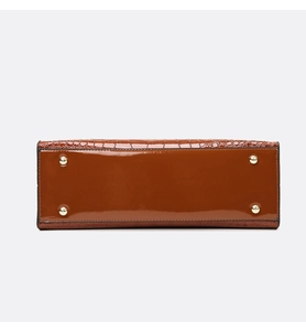 Detail of crocodile embossed handbag base featuring four protective gold metal feet studs