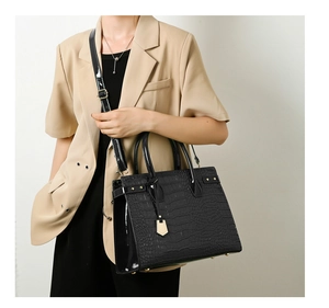 Detail of black crocodile pattern leather handbag with gold hardware and top handle