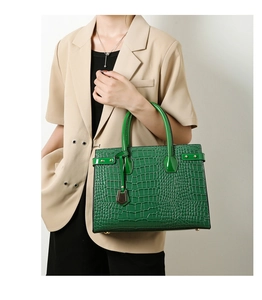 Detail of green crocodile texture handbag with gold hardware and stylish top handles