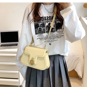 Detail of a creamy yellow leather crossbody bag featuring a golden crown metal buckle