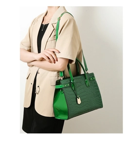 Detail of green crocodile texture handbag with gold hardware shown on a model