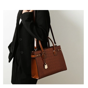 Detailed side view of dark brown crocodile embossed tote bag with gold stud accents