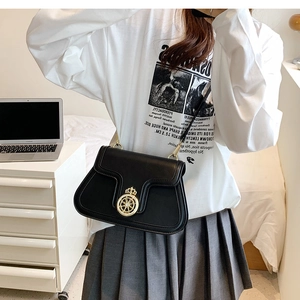 Detail of minimalist black crossbody bag with gold crown buckle on a stylish model