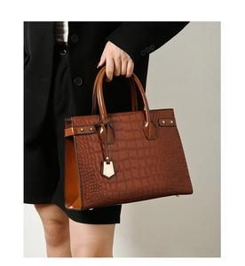 Detail of dark brown crocodile texture handbag with metal rivets and sturdy round handles