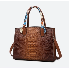 Vista detallada del bolso de mano marrón con textura de cocodrilo y pañuelo de seda floral