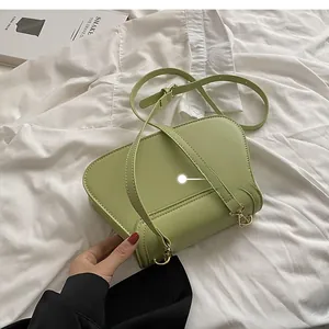 Detail view of the light green leather bag's back with golden metal strap hooks