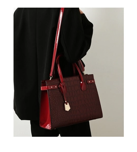 Macro view of wine red tote bag featuring crocodile texture and gold hardware details