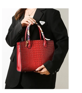 Detalle de bolso rojo con grabado de cocodrilo y elegante pañuelo de seda en el asa