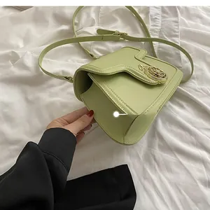 Detail view of the mint green crossbody bag side profile and its golden metal logo