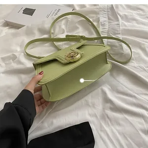 Detail showing the curved bottom and golden circular hollow lock of the sage green leather bag
