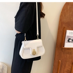 Close-up of white leather crossbody bag with vintage golden round lock and fine stitching