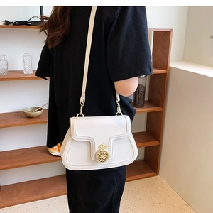 Detailed view of a white leather crossbody bag featuring a golden circular metal lock