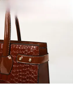 Detail shot of brown crocodile pattern lacquer leather with gold rivet accents