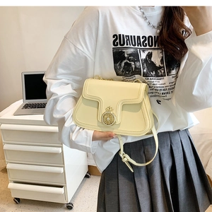 Detail of light yellow leather crossbody bag with gold crown buckle on white background