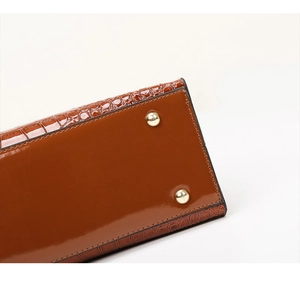 Detail view of brown crocodile embossed leather bag base with golden protective metal feet