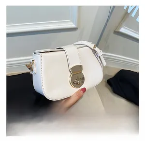 Detail of white leather saddle bag showing gold hardware buckle and refined side stitching
