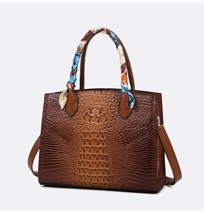 Detalle del bolso con diseño de cocodrilo, pañuelo decorativo en asa y correa de hombro