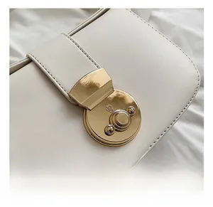 Macro shot of glossy gold rotating lock on beige leather bag with detailed stitching