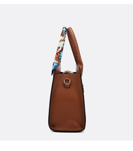 Detalle del bolso marrón caramelo con textura de cuero de lichi y pañuelo decorativo en asa
