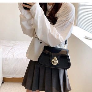 Detail of black crossbody bag with vintage golden crown buckle and slim shoulder strap