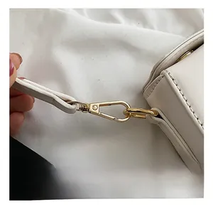 Close-up of premium gold metallic hook and stitching on white leather handbag strap