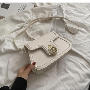 Detail of a creamy white flap shoulder bag featuring a gold crown emblem and leather strap