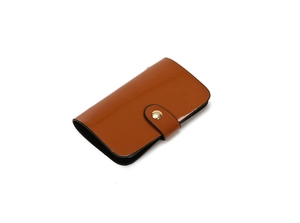 Close-up of brown patent leather small wallet with gold metallic snap button closure