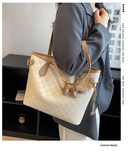 Detail of soft PU tote bag with checkered texture and cute dog charm on shoulder