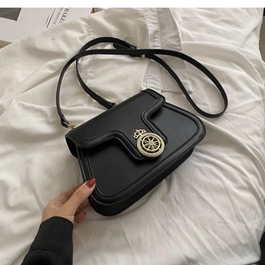 Detail of black leather crossbody bag featuring gold crown hardware and matte finish