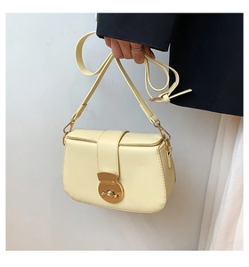 Detail of cream yellow leather shoulder bag with round golden metal clasp and strap