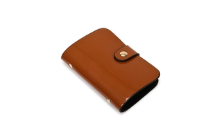 Detail of caramel brown patent leather mini wallet with glossy finish and metal snap button