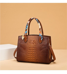 Detalle de bolso marrón con estampado de cocodrilo con asa de seda y correa ajustable